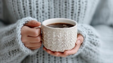 Woman in Blue Sweater Holding Speckled Mug of Dark Coffee with Soft Lighting in Neutral Background