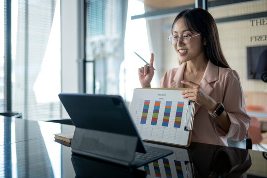 Asian businesswoman presenting sales report using tablet during a video conference