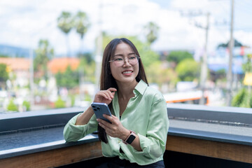 Smiling businesswoman using smartphone on balcony in urban setting