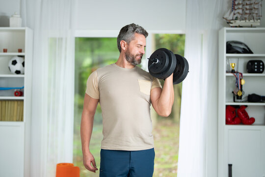 Middle-Aged Man Lifting Dumbbells at Home. Fit Latin Man Exercising with Weights. Mature Man with Dumbbells Indoors. 40s man Lifting Dumbbells. Morning Exercises. Training with Dumbbells.