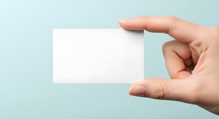 Obraz premium Hand Holding Blank Card Mockup for Business or Invitation Design on Blue Background