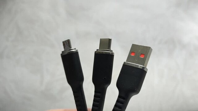 A black USB charging cable in the hand. The cable has a standard USB connector , micro and type-c