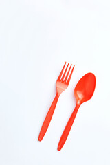 A red plastic fork and spoon placed side by side on a clean white background.