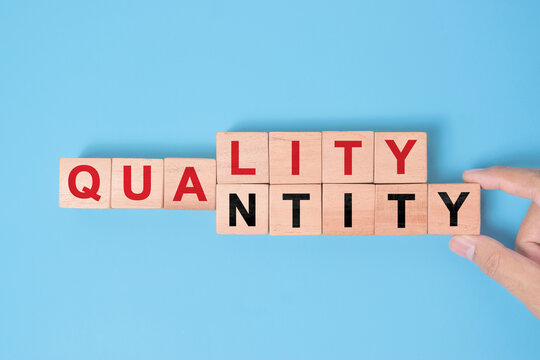 Quality over quantity concept. Hand changing word quantity to quality on wooden blocks.