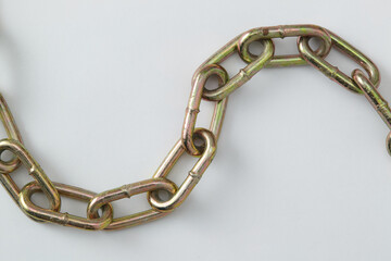 A close-up photo of a metallic chain with oval links, arranged in a curved shape on a light...
