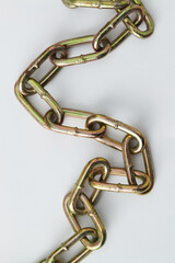 Metal chain with large oval-shaped links that are connected to each other, has a shiny surface with a greenish golden colour