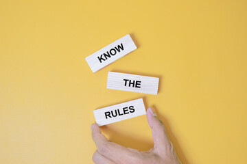 Know the rules symbol. Wooden blocks with words Know the rules. Beautiful orange background. Businessman hand. Business and Know the rules concept