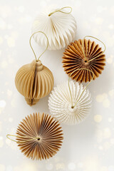 Festive trendy paper Christmas ornaments beige brown colored on white background with golden bokeh. Spheres, honeycomb balls, flashlight. Scandinavian holiday atmosphere, creative flat lay, copy space
