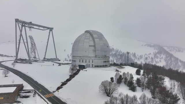 An aerial view of the BTA 6 and Special Astrophysical Observatory located in the Republic of Karachay-Cherkessia, Russia. The observatory is covered in snow on a cloudy winter day