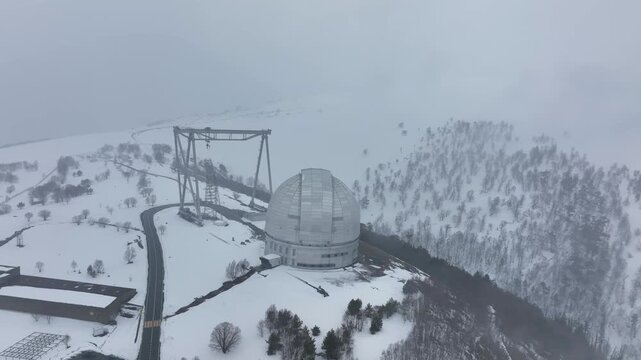An aerial view of the BTA 6 and Special Astrophysical Observatory located in the Republic of Karachay-Cherkessia, Russia. The observatory is covered in snow on a cloudy winter day