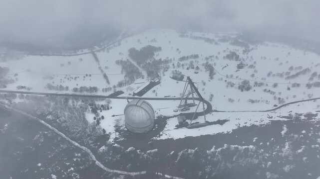 An aerial view of the BTA 6 and Special Astrophysical Observatory located in the Republic of Karachay-Cherkessia, Russia. The observatory is covered in snow on a cloudy winter day