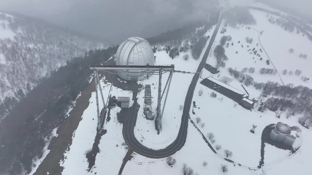 An aerial view of the BTA 6 and Special Astrophysical Observatory located in the Republic of Karachay-Cherkessia, Russia. The observatory is covered in snow on a cloudy winter day