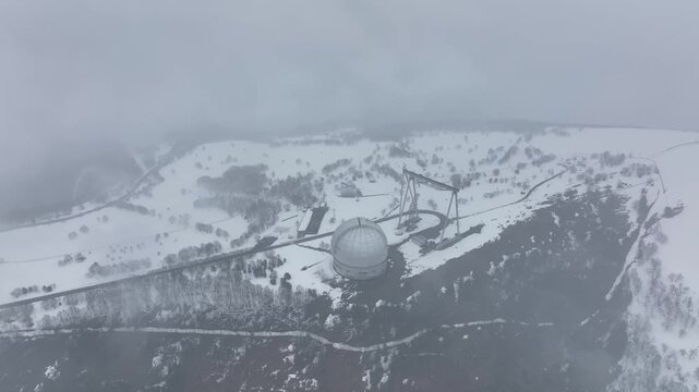 An aerial view of the BTA 6 and Special Astrophysical Observatory located in the Republic of Karachay-Cherkessia, Russia. The observatory is covered in snow on a cloudy winter day