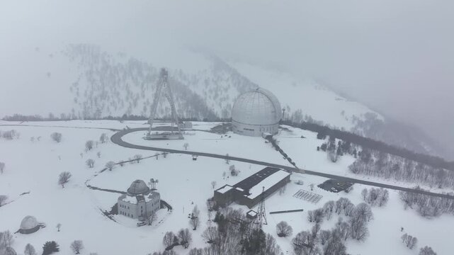 An aerial view of the BTA 6 and Special Astrophysical Observatory located in the Republic of Karachay-Cherkessia, Russia. The observatory is covered in snow on a cloudy winter day