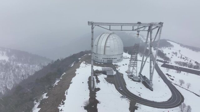 A close up of the BTA 6 and Special Astrophysical Observatory dome in the Republic of Karachay-Cherkessia, Russia. The observatory is covered in snow on a cloudy winter day