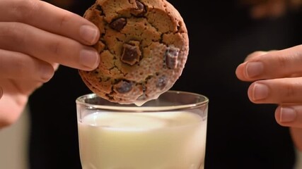 Delicious chocolate chip cookie being dunked into a creamy glass of fresh milk treat - Powered by Adobe