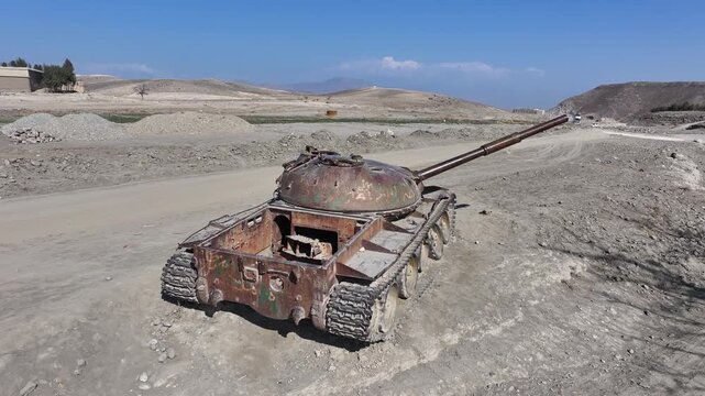 Destroyed rusty old military tank Soviet T62 in Afghanistan, drone circling around, Nangahar, Nuristan from Soviet American war in desert landscape, Khogyani district. marks of war torn country