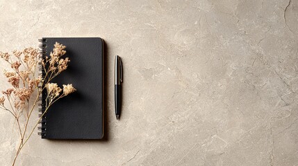Flat Lay of Black Notebook and Pen on Beige Stone Surface