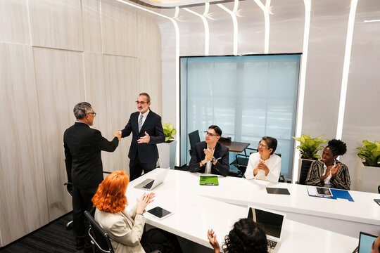 Diverse colleagues applaud as two professionals shake hands in modern conference room. Business meeting scene shows partnership, sales, leadership, planning, collaboration, and networking seminar. - Powered by Adobe