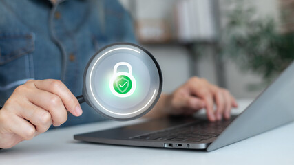 Businessman using a laptop with a magnifying glass showing security lock icon, cybersecurity, data...