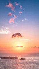 Vertical ocean view with small islands. Sunset on the horizon with clouds that are pink and orange reflecting on the ocean