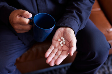 錠剤の薬と日本人シニア男性の手元