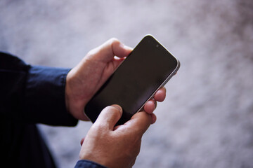 スマートフォンを操作する日本人シニア男性の手元