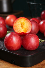 Fresh Red Plums Cut in Half Showing Golden Flesh on Dark Slate Board