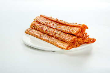 Spicy beef jerky strips with chili seasoning on white plate - handmade dried meat snack high protein food photography