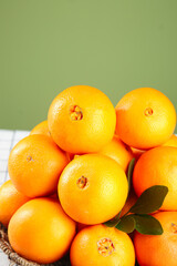 Fresh Navel Oranges in Wicker Basket with Green Leaves on Olive Background
