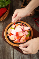 Fresh Mixed Radish Pickle Bowl with Carrots and Vegetables Held by Hands on Wooden Table
