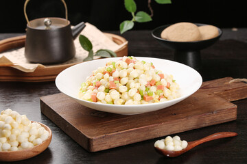 Stir-fried corn kernels with ham and vegetables in white bowl on wooden board, healthy homemade cooking