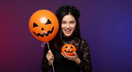 Happy Asian woman in a Halloween costume holding a jack-o'-lantern balloon. Young person celebrating a festive holiday party. Fun October celebration concept with copy space