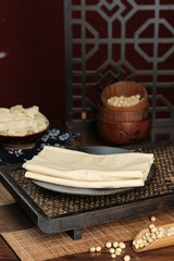 Handmade Tofu Skin Sheets with Raw Soybeans on Traditional Woven Tray - Asian Food Ingredients