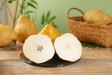 Fresh Asian pears sliced in half on rustic wooden table with natural basket display