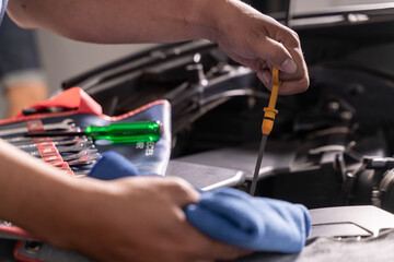 Young man checking engine oil level in his car, concept of car maintenance, vehicle safety, and automotive care.