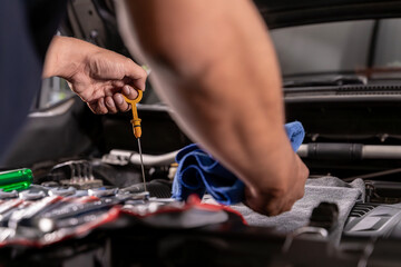 Young man checking engine oil level in his car, concept of car maintenance, vehicle safety, and automotive care.