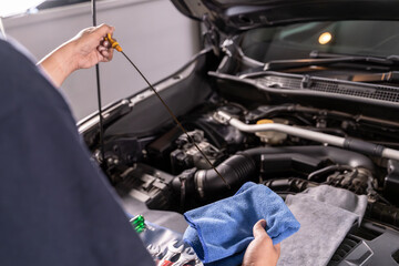 Young man checking engine oil level in his car, concept of car maintenance, vehicle safety, and automotive care.