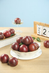 Obraz premium Fresh Red Chilean Plums in Bowl with April Calendar - Healthy Organic Stone Fruit Photography