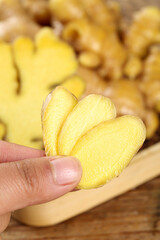 Fresh Ginger Root Slices in Hand on Wooden Cutting Board - Natural Spice Ingredient for Cooking and Health