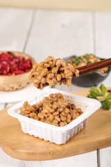 Japanese Natto Fermented Soybeans with Chopsticks Showing Sticky Texture on Bamboo Serving Board