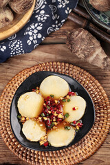 Fragrant Shandong-style small taro slices with garnish in traditional woven basket setting on rustic wood table