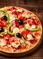 Pizza with salami, mozzarella cheese and jalapeno pepper. Wooden background. Soft focus.	