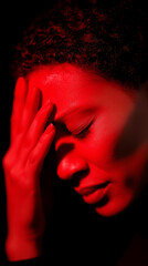 Woman with headache holding her head under red light. 

