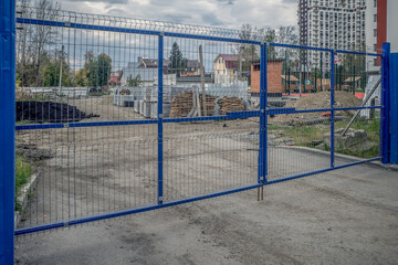 Closed steel gates of a construction site on an autumn day