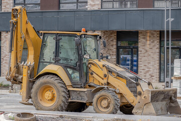 A wheeled excavator is parked at the construction site of an apartment building on an autumn day