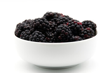A close-up shot of a white bowl filled with fresh, ripe, and juicy blackberries, isolated on a white background.