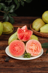 Fresh Red Guava Fruit Sliced on Plate Showing Pink Flesh and Seeds on Rustic Wood Background