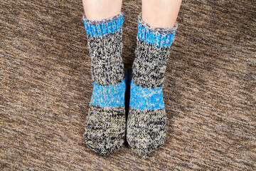 A pair of homemade knitted socks on women's feet. Warm wool socks