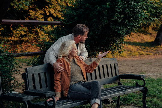 Senior couple relaxing on bench and enjoying conversation in park